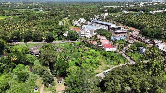 A breathtaking aerial footage shows a colourful town nestled at majestic foothills. The dense settlement, surrounded by lush coconut trees.
