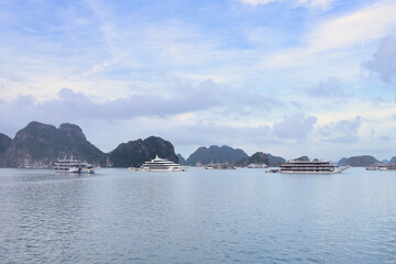 Ha long bay. An iconic unesco world heritage site. Displaying numerous limestone karsts emerging from the serene emerald waters. With various tourist cruise vessels navigating the picturesque seascape