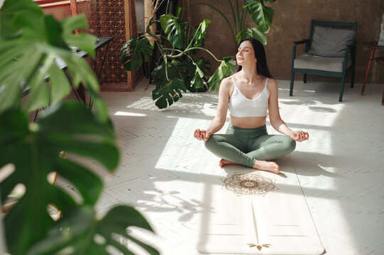 Charming lady performing padmasana exercise with closed eyes