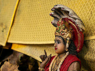 Obraz premium Hindu God Vishnu Statue in Red Robes with Golden Crown and Ornate Jewelry Sitting on Lotus Throne