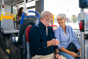 Happy senior couple sitting on a city bus, enjoying public transport and talking, symbolizing urban life retirement