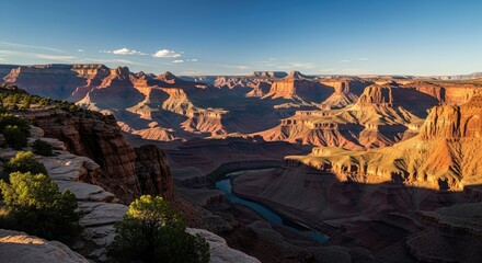 Grand canyon landscape with river and rock formations under blue sky