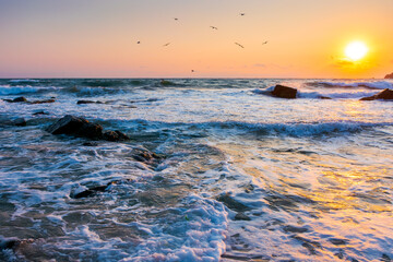 beautiful sunrise at the sea beach. sandy coast with rock. summer vacation background. sun over...