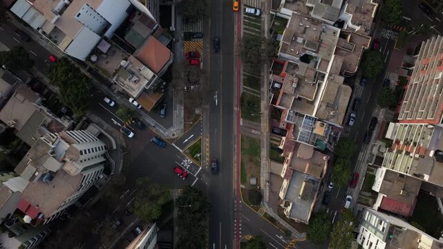 High altitude top down aerial shot flying over a street intersection in Lima, Peru. Cars and taxis moving through urban city traffic