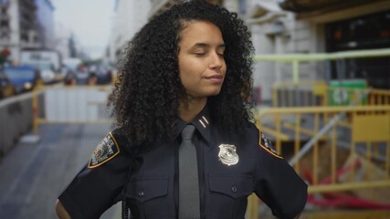 Policewoman in uniform smiles at a construction site, showcasing a confident presence outdoors in an urban setting, emphasizing a hispanic american woman on duty.
