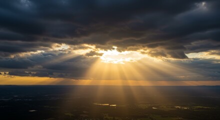 Golden Sunbeams Breaking Through Dark Clouds Over Landscape