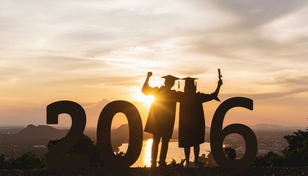 Two triumphant graduates celebrate their success holding diplomas silhouetted against a breathtaking sunset, marking a new beginning.