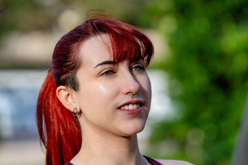 Young woman with red hair and nose ring smiling