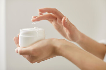 Close up of female hands holding cosmetic cream jar, lady trying moisturizing revitalizing creme lotion on finger for applying on hand, face, body skin to advertise skin care, beauty spa treatment 