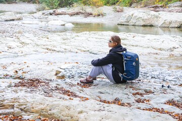  young girl with a backpack is hiking alone in nature