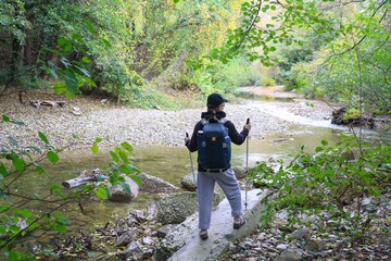  young girl with a backpack is hiking alone in forest
