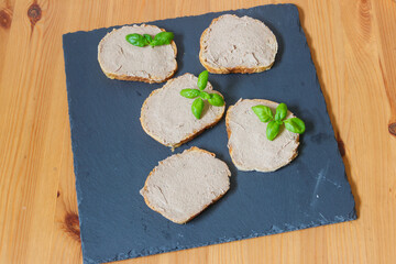 Sandwiches with pate on a slate board on wooden table