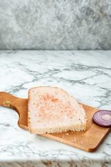 Raw fish fillet and red onion slices on a wooden cutting board