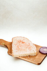 Raw fish fillet and red onion slice on wooden cutting board