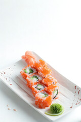 Delicious salmon roe sushi rolls on a white plate with wasabi
