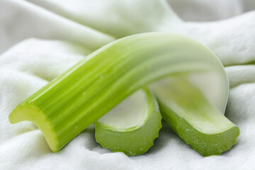 Fresh green celery stalks on a white fabric background