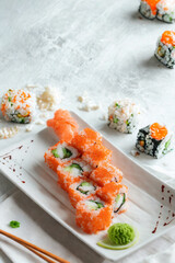 Fresh salmon and cucumber sushi rolls on a white platter