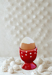 Red egg cup holds boiled egg surrounded by decorative stones