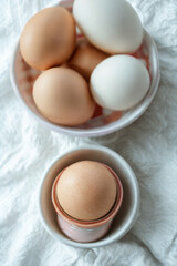 Fresh farm eggs in bowls on a textured white surface