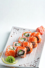 Freshly prepared sushi rolls with tobiko and cucumber on a white plate