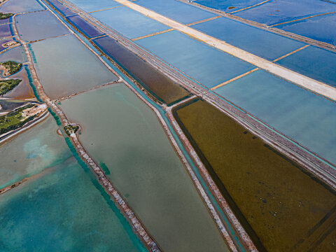 Aerial view of salt pans reflecting sky with geometric precision and earthy tones, creating a mosaic of textures, El Puerto de Santa Mar&Atilde;&shy;a, Andalusia, Spain.