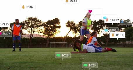 Sliding female soccer player wearing bib gliding across pitch at sunset, with notification icons