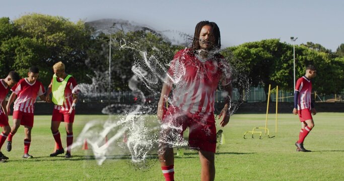 Training male wearing soccer uniform stepping forward on field, with cones and agility hurdles - Powered by Adobe