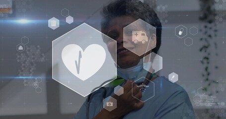 Clinician in scrubs adjusting mask and stethoscope in clinic, with hexagonal healthcare icons