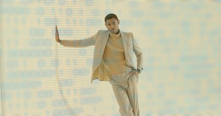 Leaning male model wearing beige suit pushing palm forward in studio, with binary code overlay