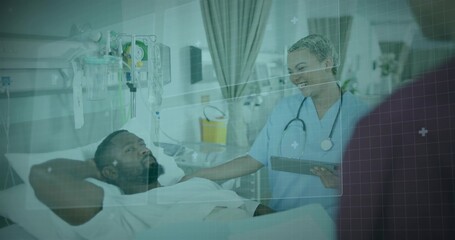 Nurse in scrubs, doctor in coat consulting patient in hospital bed, with IV stand and tablet