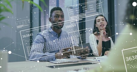 Two business casual professionals discussing analytics with tablet in conference room with overlays