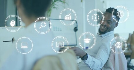 Gesturing male explaining analytics using dual monitors with digital icons in workspace, copy space