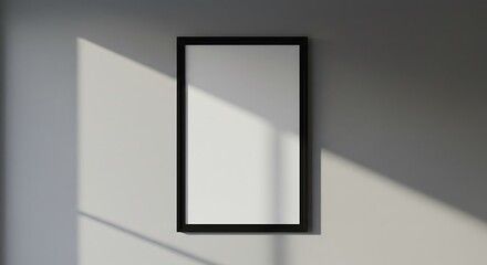 Sunlight casting shadows on a blank vertical picture frame mounted on a plain wall, ideal for showcasing art or photography