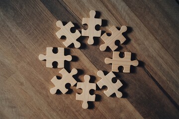 Wooden puzzle pieces creatively arranged on a rustic wood surface suggesting teamwork, problem-solving, and strategic thinking in a visually appealing manner