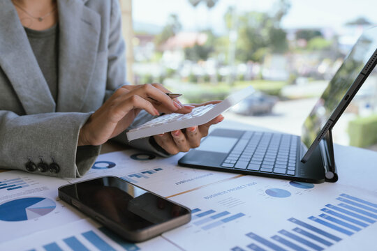 Businesswoman analyzing financial charts and data reports with a laptop at the office, planning strategy and performance review.