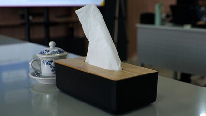 A tissue box and a cup placed on a table