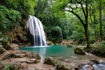 Fototapeta premium Tropical waterfall into a vivid turquoise pool, lush green jungle.