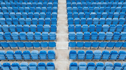 Symmetrical blue stadium seats from above, a serene geometric pattern of empty spaces