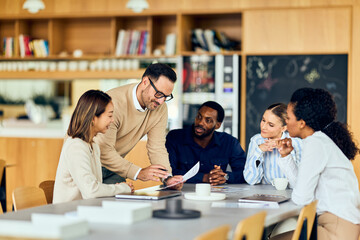 Diverse Team Collaborating in a Business Meeting, Discussing Ideas Over Papers and Coffee Together Energetically