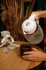 Making tea at home: a woman takes tea bags out of a jar next to an electric kettle