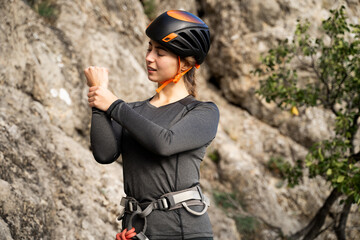 Portrait of young woman climber holding wrist in pain near rock in nature, concept of overuse injury, recovery, body care and awareness in outdoor physical activity