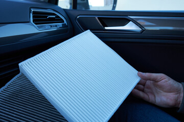 A close-up of a car air conditioner filter in a man's hands. Filter replacement.