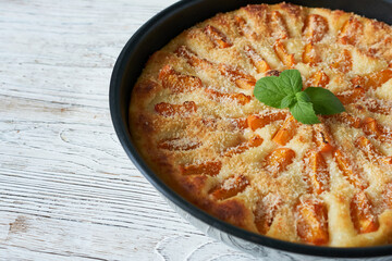 Homemade apricot pie in a baking dish on a wooden background