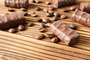 Chocolate candies and coffee beans on wooden background, closeup