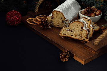 Christmas stollen on a wooden board with green branches of a Christmas tree. Christmas background, Christmas desserts