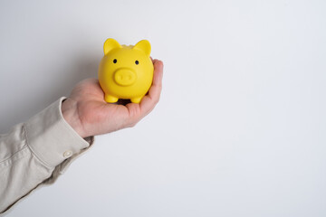 Man holding a yellow piggy bank and magnifying glass. Symbol of saving money, investment growth and smart financial planning. Concept of personal finance, economy, and budget management.
