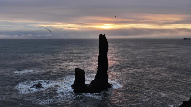 Aerial view of basalt sea stacks stand defiant against the North Atlantic, their dark forms contrasting with the moody sky, Iceland.