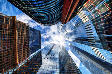 Looking directly up at the skyline of the financial district in London with clouds passing by, background for modern architecture and urban cityscapes