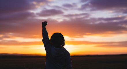 Empowered silhouette raising fist in victory against a beautiful sunset sky