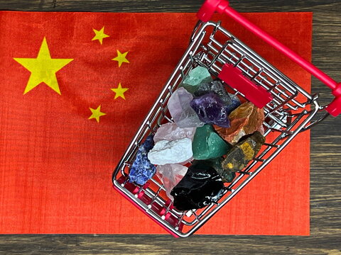 The flag of China and a shopping cart with various stones and minerals. Rare earth metals.